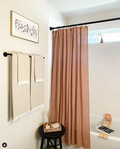 a bathroom with a shower curtain, stool and pictures on the wall in front of it