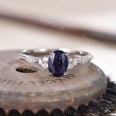 a blue and white diamond ring sitting on top of a piece of metal next to a brush