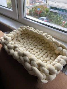 a knitted basket sitting on top of a window sill next to a window