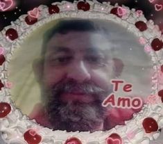 a man with a beard is looking at the camera in front of a heart - shaped cake