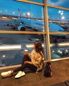 a woman sitting in front of an airport window