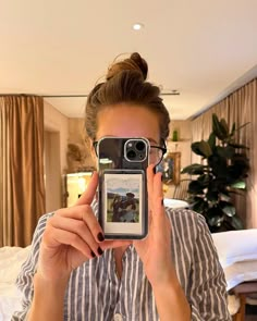 a woman taking a selfie with her cell phone while sitting in front of a bed