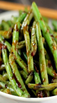 a white bowl filled with green beans on top of a wooden table