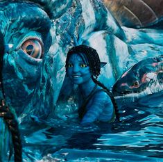 a woman with dreadlocks standing in the water next to a giant fish