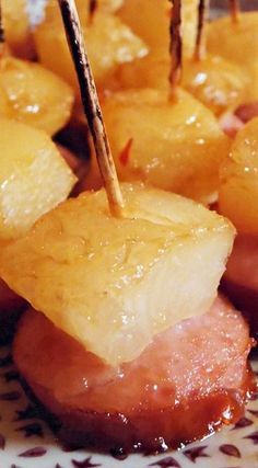 pineapple and ham skewers on a plate with toothpicks in them