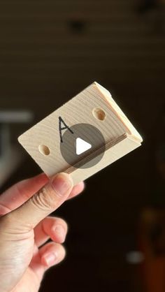 a person holding up a piece of wood with a video game logo on the front