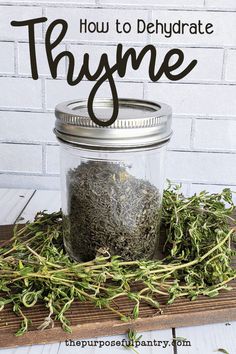 a jar filled with thyme sitting on top of a wooden table