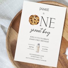 a card with a cookie on it sitting on top of a wooden plate next to cotton