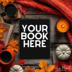 an ipad surrounded by autumn leaves, candles and pumpkins on a wooden table with the words your book here