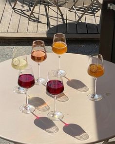 four glasses of wine sitting on top of a table next to each other in front of a chair