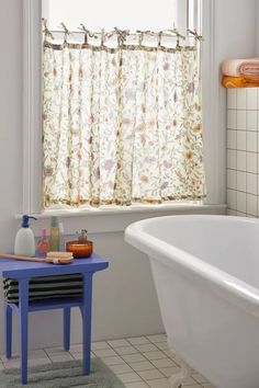 a bath tub sitting next to a window with a curtain on it's side