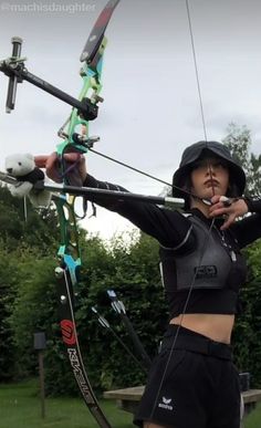 a woman in black shirt and shorts holding up a bow