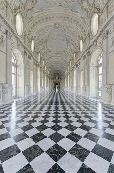 an empty hallway with black and white checkered flooring on one side and windows in the other