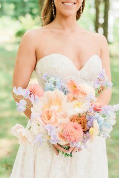 a woman holding a bouquet of flowers in her hands and smiling at the camera while wearing a strapless wedding dress