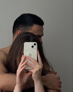 a man and woman hugging each other while holding their cell phones in front of them