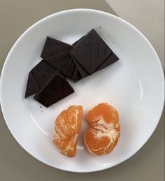 three pieces of chocolate and an orange on a white plate