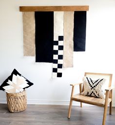 two black and white rugs hanging on the wall next to a chair with a pillow