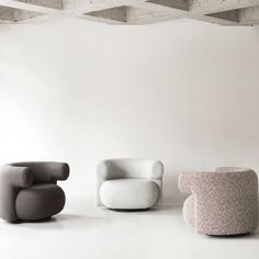 three different colored chairs sitting next to each other on a white floor in front of a wall