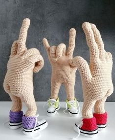 three knitted hand puppets with one holding the other's fingers up in different colors