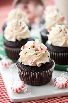 chocolate cupcakes with white frosting and candy canes on a tablecloth