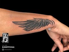 a hand with a black wing tattoo on it