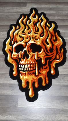 an orange and black skull with flames on it's face is sitting on the floor