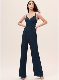 a woman is wearing a jumpsuit with straps on the side and her hands behind her back