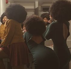 a group of women standing in front of a bathroom mirror looking at their selfs