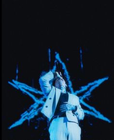 a man in white suit standing on stage