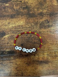 a beaded bracelet with the word wow on it sitting on top of a wooden table