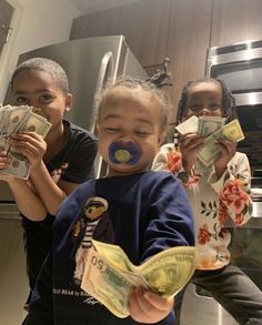 three children holding money in front of their faces and smiling at the camera, while another child holds out dollar bills to her face