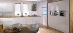 a modern kitchen with white cabinets and wood flooring is pictured in this image from the dining room