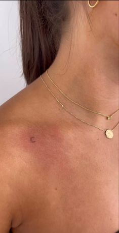 the back of a woman's neck with a small gold disc on her left shoulder