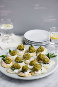 small appetizers are arranged on a plate next to wine glasses and napkins