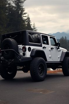 a white jeep parked on the side of a road near some trees and mountains in the background