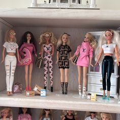 several barbie dolls are lined up in a toy closet with clothes and purses on the shelves