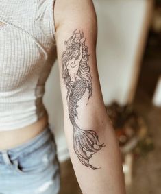 a woman with a mermaid tattoo on her arm