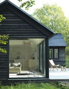 a small black cabin with sliding glass doors on the front door and patio area outside