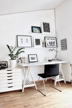 a white desk with black chairs and pictures on the wall