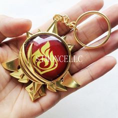 a hand holding a red and gold keychain with an emblem on the front