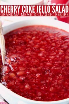 cherry coke jello salad in a white bowl with a wooden utensil sticking out of it