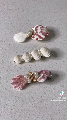 three seashells with pearls on them sitting on a white counter next to each other