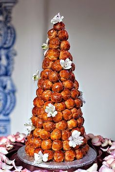 a tower of donuts on top of a table with pink and white flowers around it