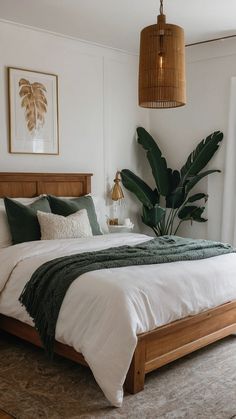 a bed with white sheets and green blankets in a bedroom next to a window, potted plant on the wall