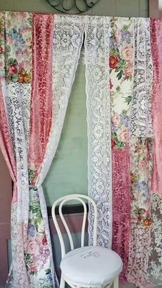 a white chair sitting in front of a window covered in pink and white laces