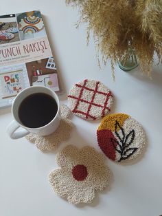 three crocheted coasters sitting on top of a table next to a cup of coffee