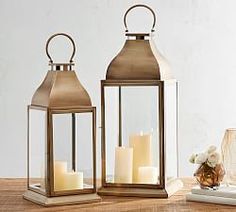 two metal lanterns with candles sitting on a table