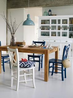 a dining room table with blue chairs and a white hutch in the back ground