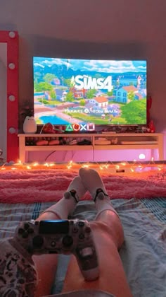 a person laying on a bed in front of a tv with a video game controller