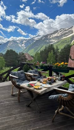 two people sitting at a picnic table on a deck with mountains in the back ground